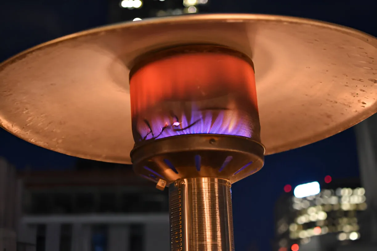 Outdoor gas patio heater with blue and red flames burning at night