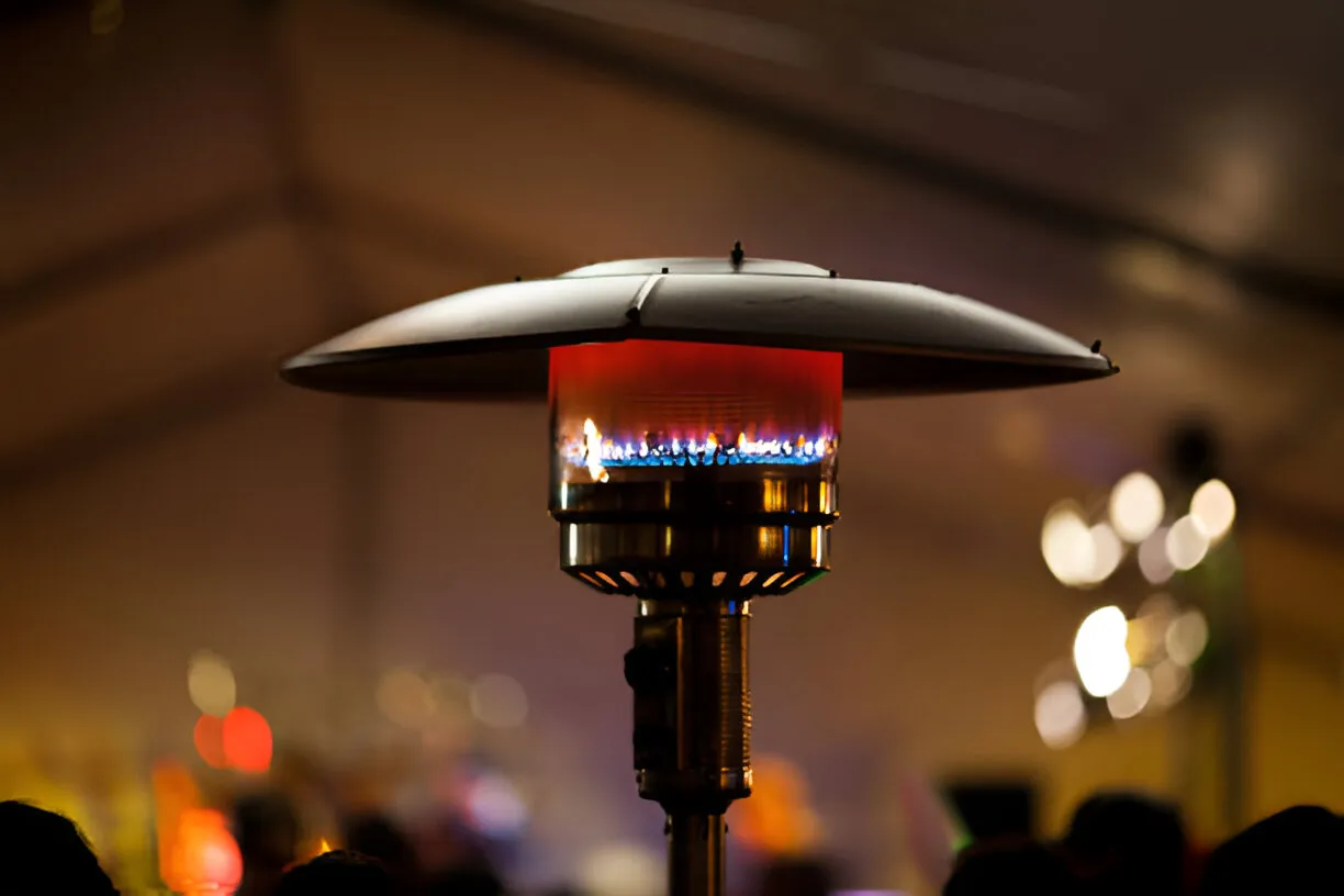 Outdoor gas patio heater with colorful flame burning at night