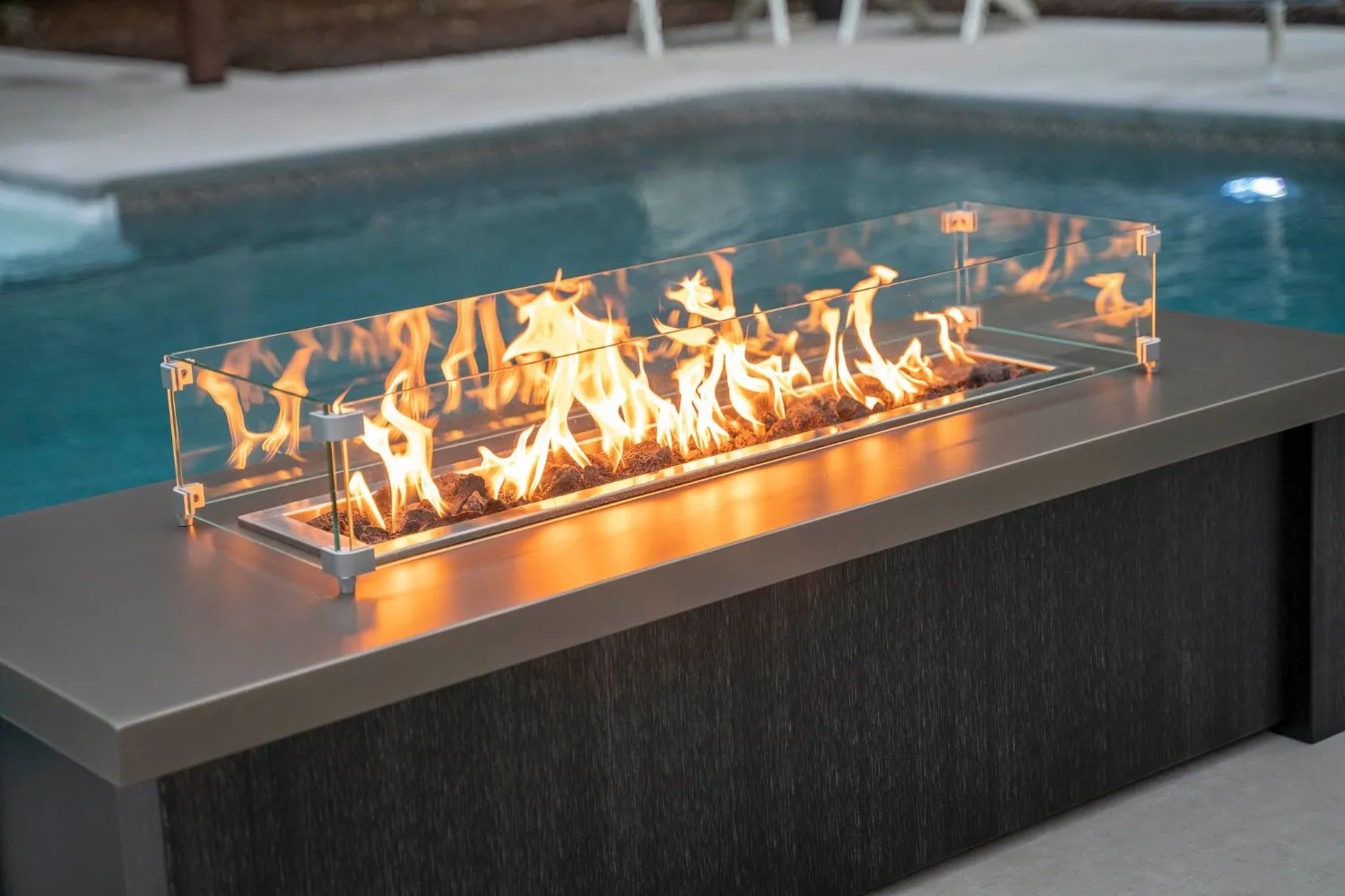 Modern outdoor fire pit with bright flames near swimming pool