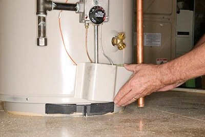 Hand adjusting pressure valve on residential water heater tank