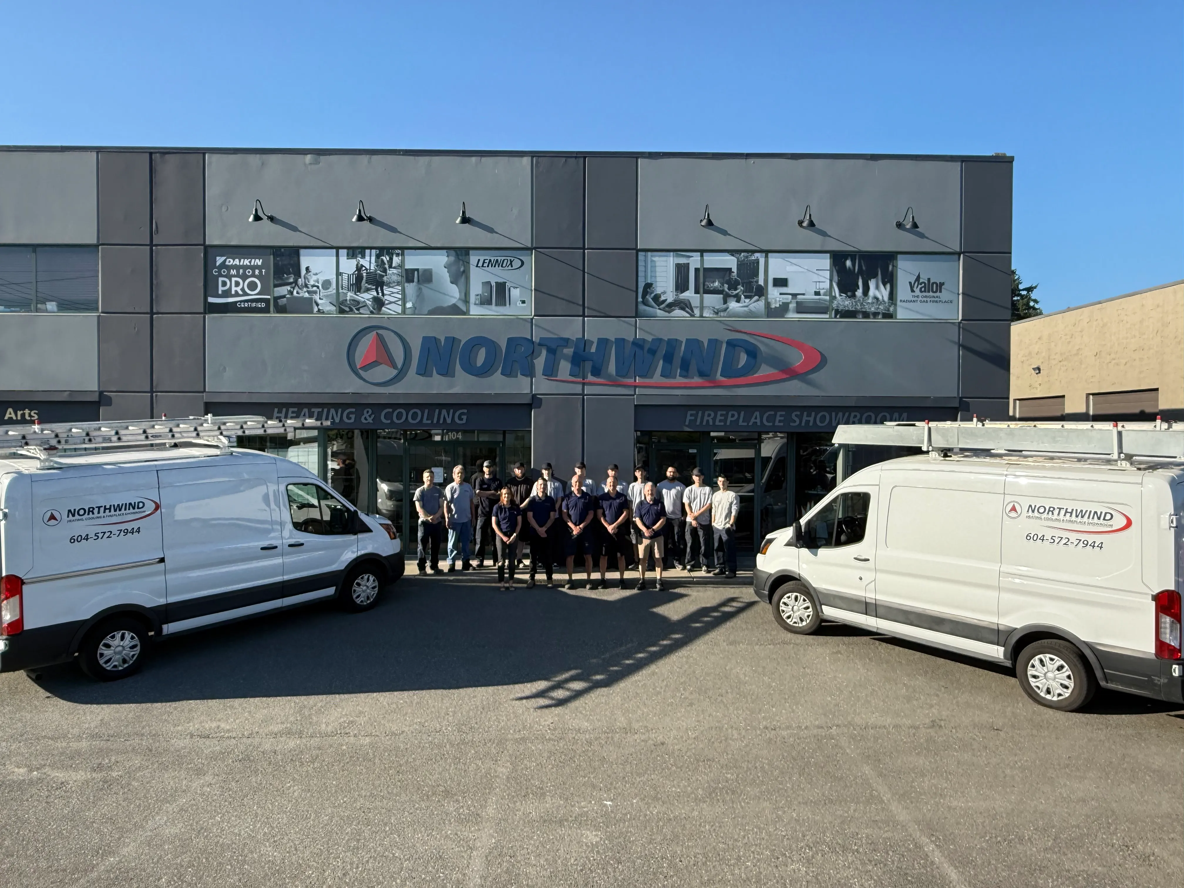 Northwind Heating & Cooling team posing in front of their business with service vans