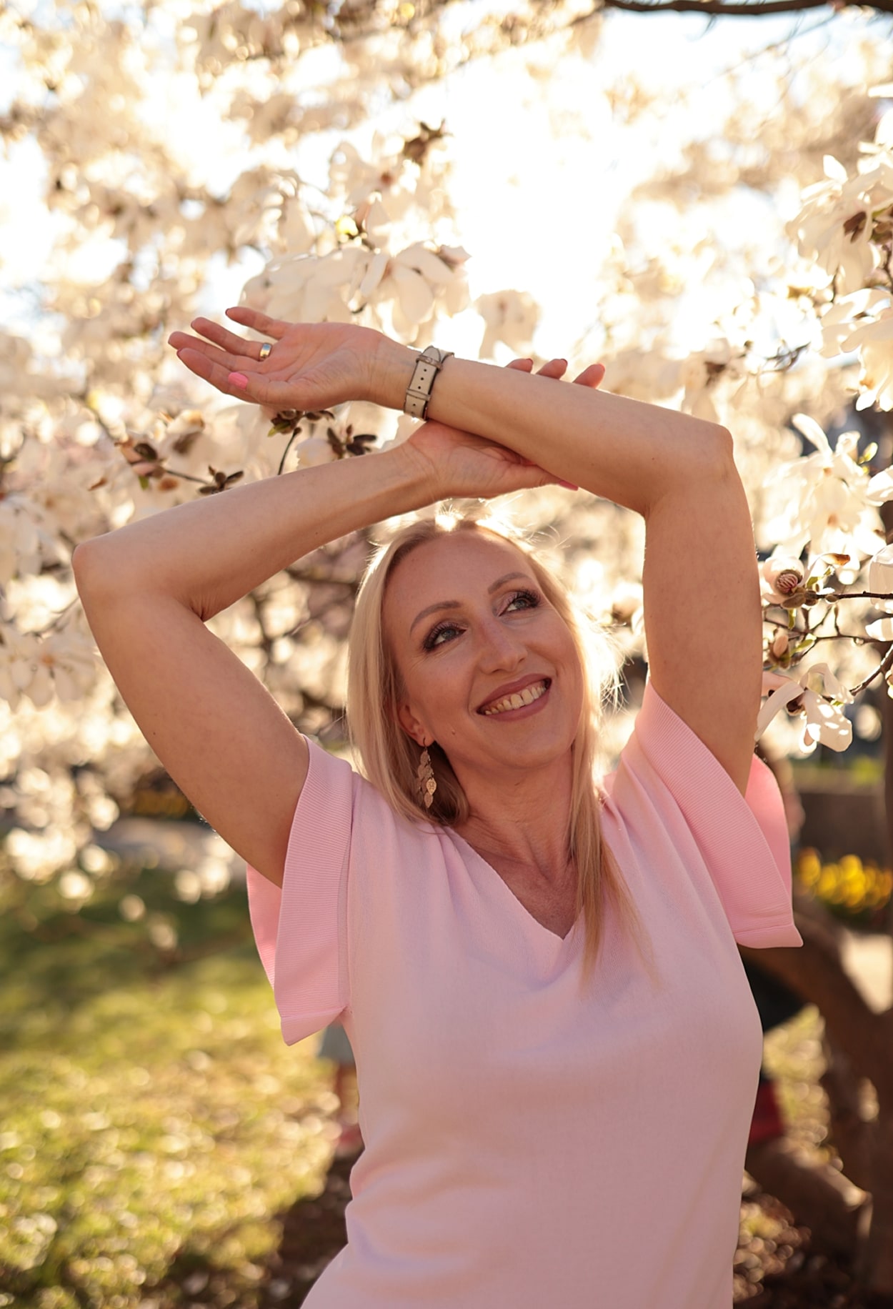 Judith mit erhobenen Armen vor einem blühenden Baum im Sommer