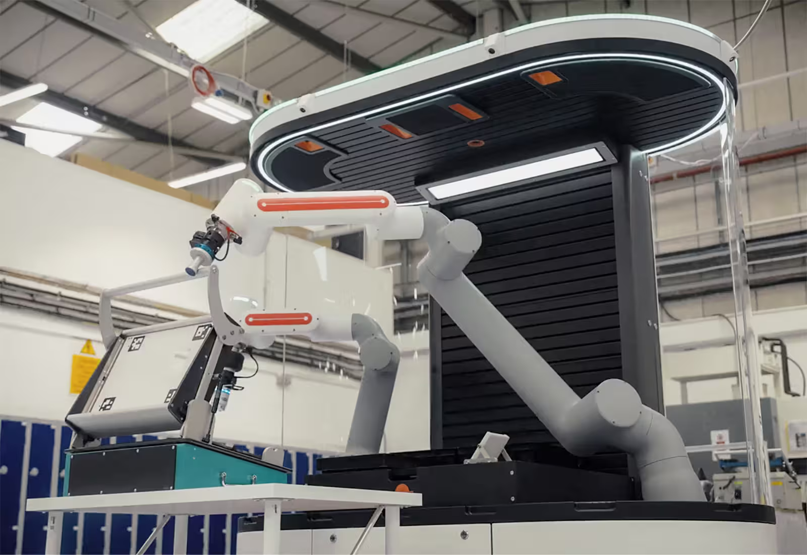 Industrial robotic arms operating inside a modern manufacturing facility with equipment and lockers.