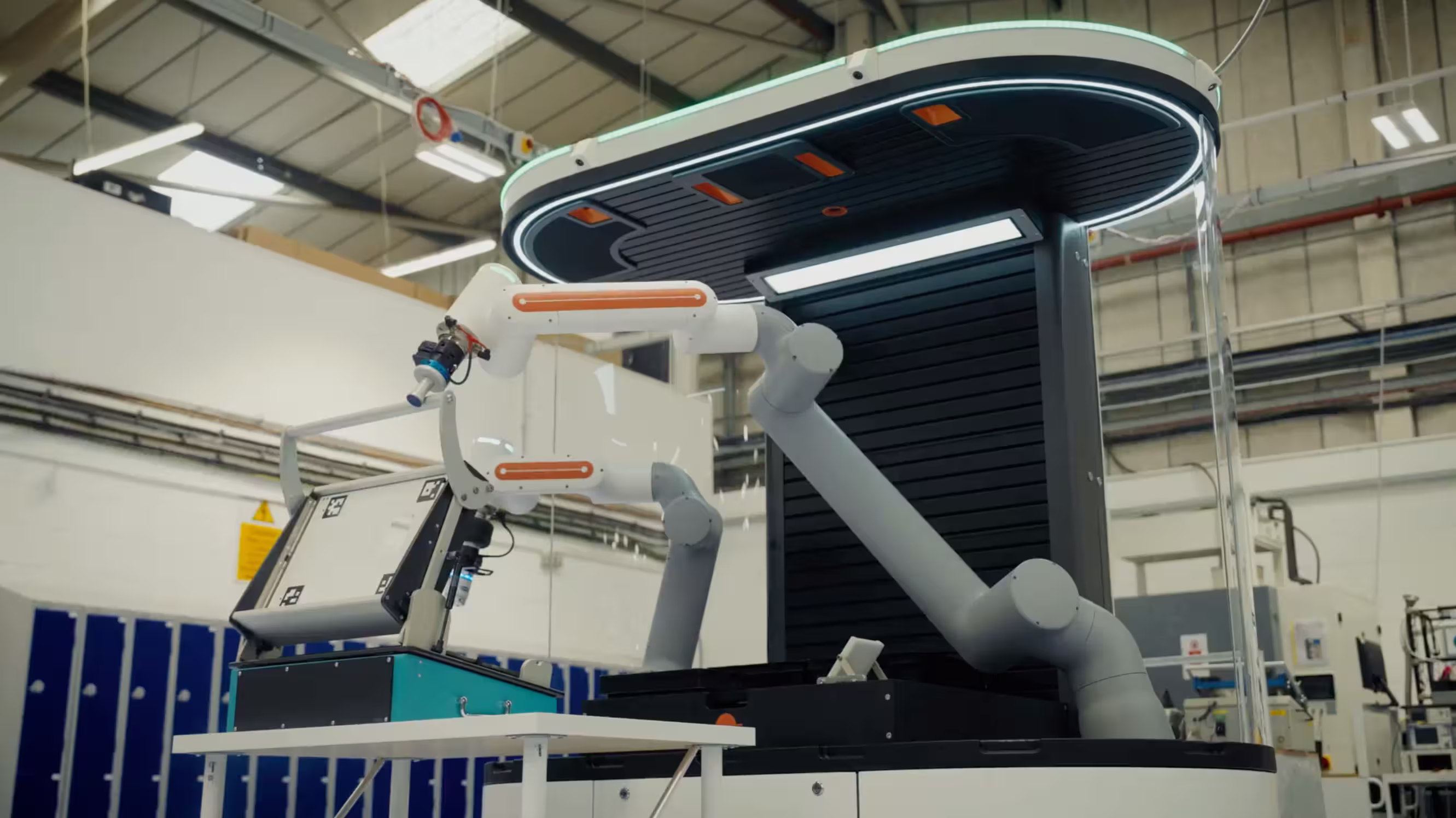 Industrial robotic arms operating inside a modern manufacturing facility with equipment and lockers.