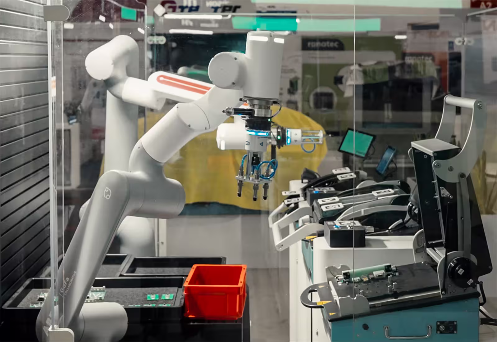 White robotic arm assembling or handling electronic circuit boards in a lab or factory setting.