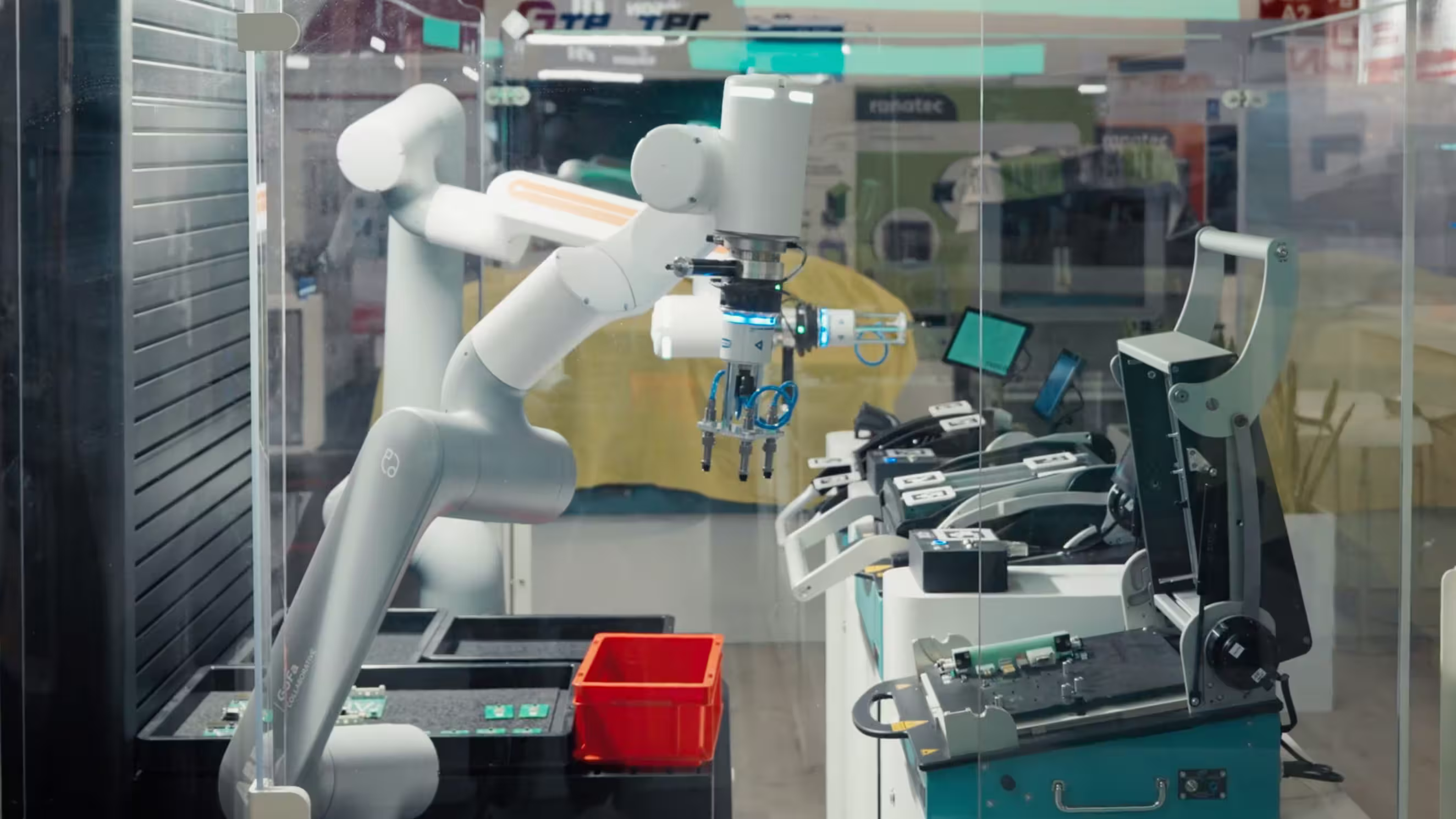 White robotic arm assembling or handling electronic circuit boards in a lab or factory setting.