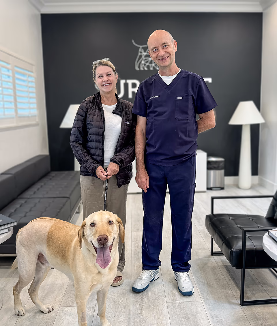 Dr. Jaroslaw Wypart, chief surgeon, with a pet owner and her yellow Labrador at a recheck visit after TPLO surgery at SurgiPet