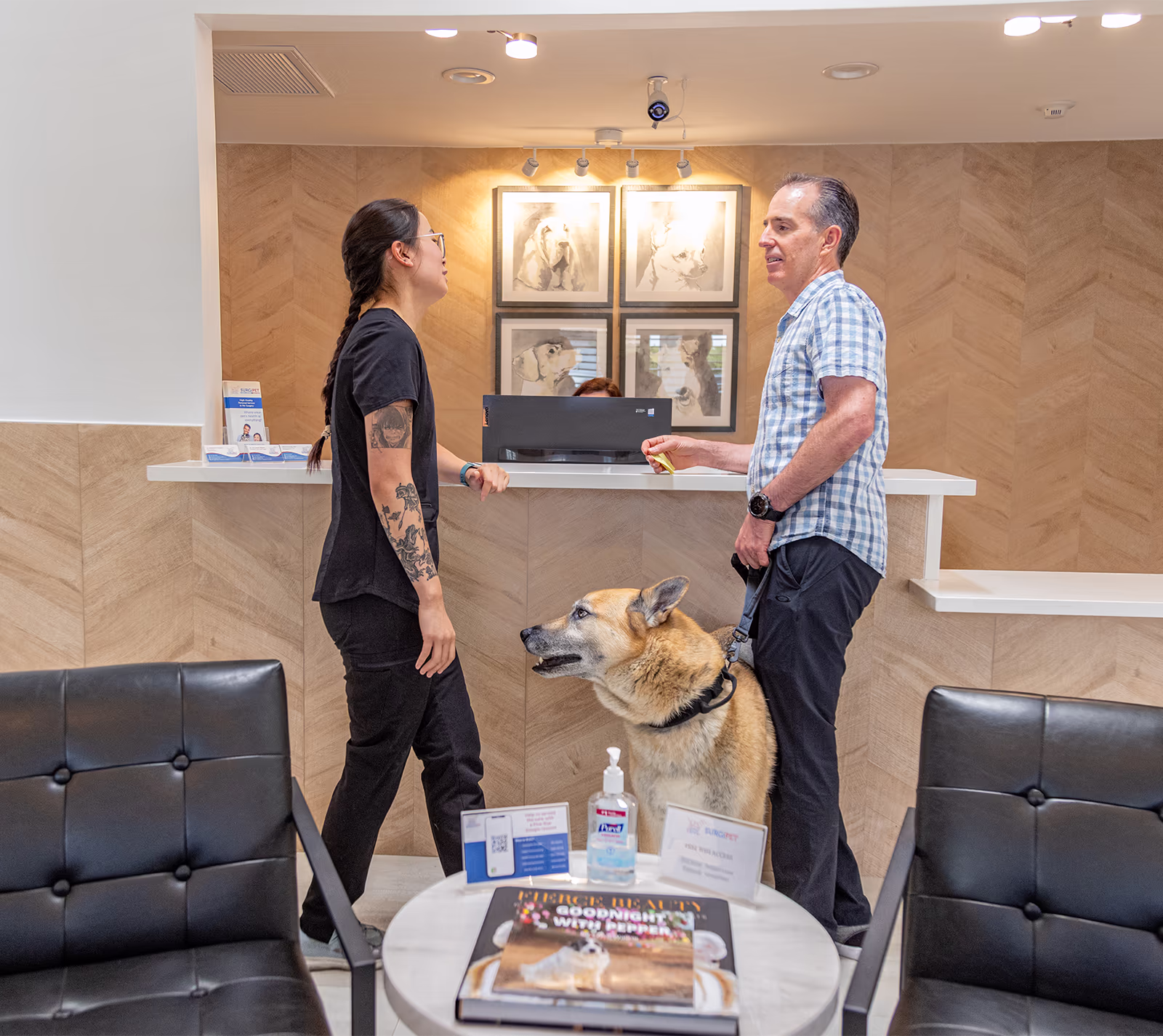 A pet owner with a German Shepherd on a leash talking with a team member at the SurgiPet front desk