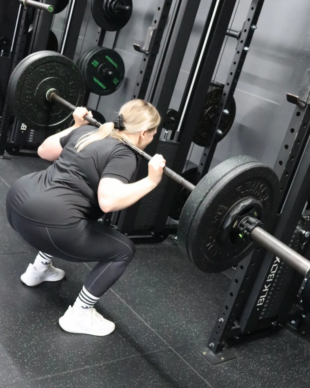 HUSTLE member doing a back squat in the gym