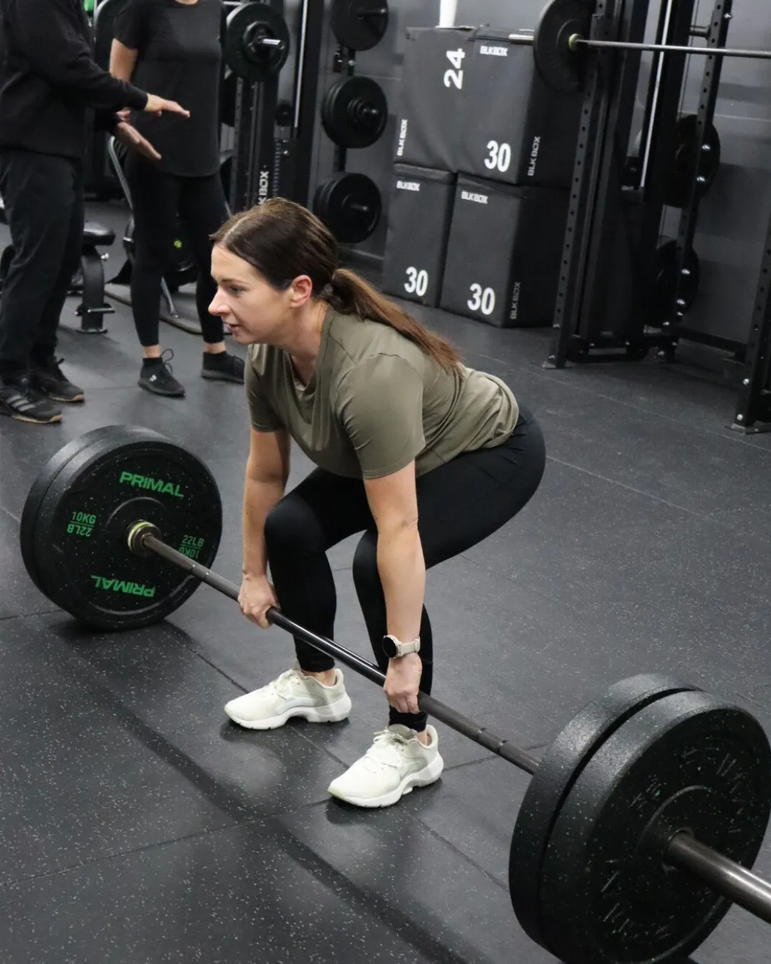 A HUSTLE member doing a deadlift smiling