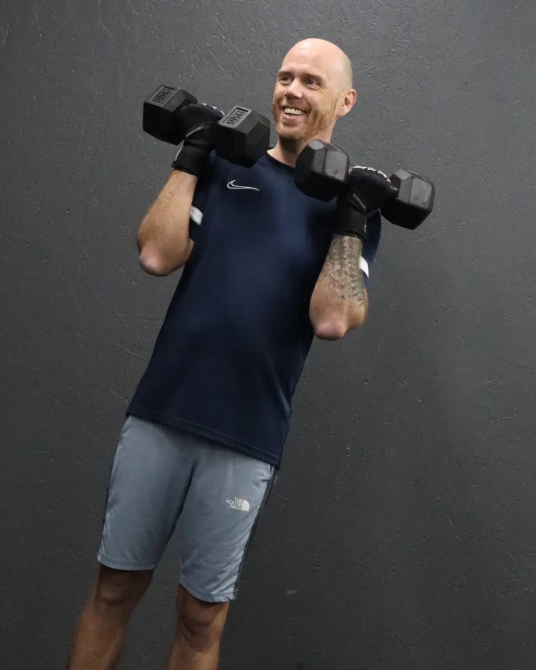 A HUSTLE gym member holding dumbbells