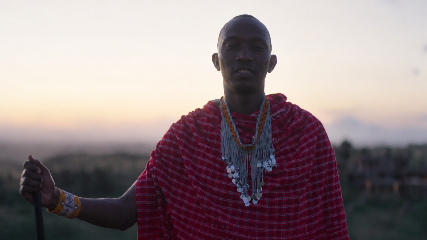 A person in Maasai attire outdoors at Osiligilai Maasai Lodge