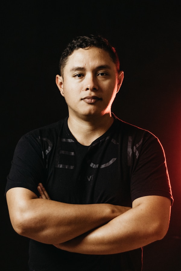 a man standing with his arms crossed in front of a red light