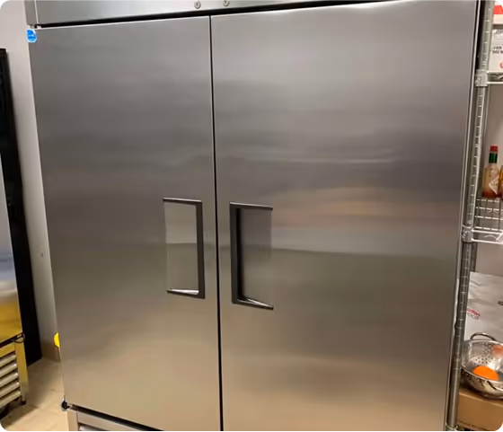 Large stainless steel commercial refrigerator with two doors in kitchen