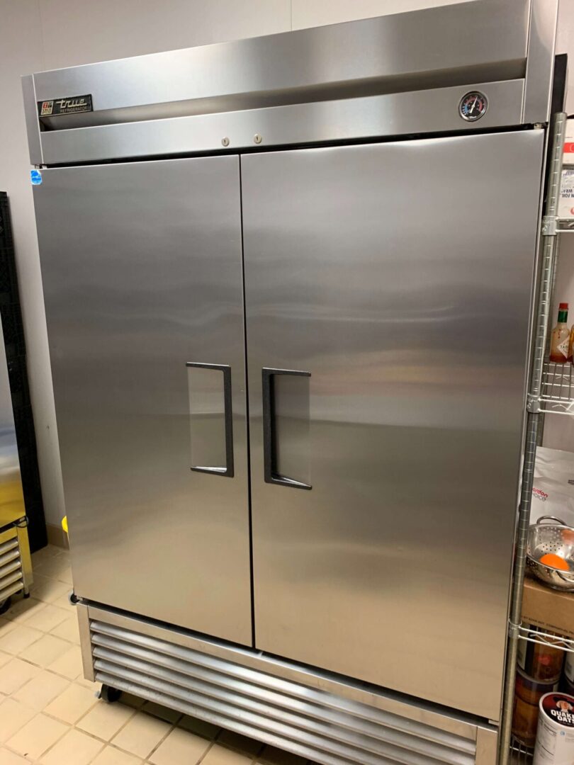 Large stainless steel commercial refrigerator with two doors in kitchen