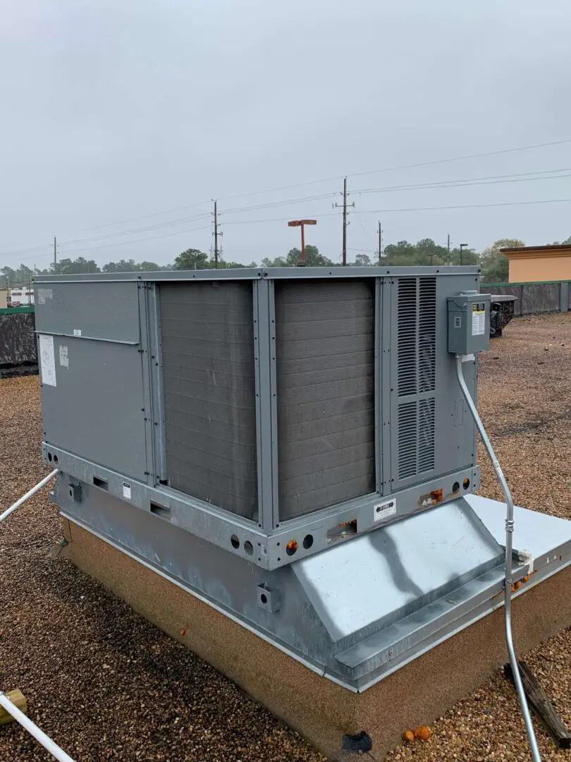 Large commercial HVAC unit installed on concrete pad with power lines