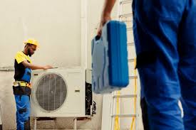 Worker in hard hat installs air conditioning unit on white wall