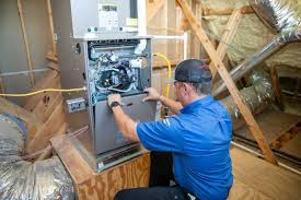 Technician in blue shirt installing HVAC system in wooden-framed attic space