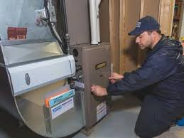 Technician in blue jacket inspecting industrial heating or electrical equipment