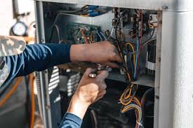 Electrician working on electrical panel with exposed wires and circuit breakers