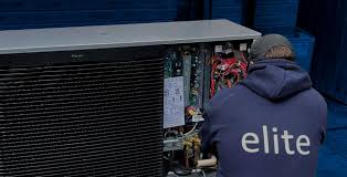 Technician in Elite hoodie working on electrical panel of large equipment