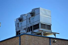 Large industrial HVAC unit mounted on brick building roof against blue sky