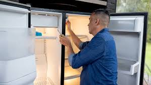 Person in blue jacket loading boxes into refrigerator or cooler