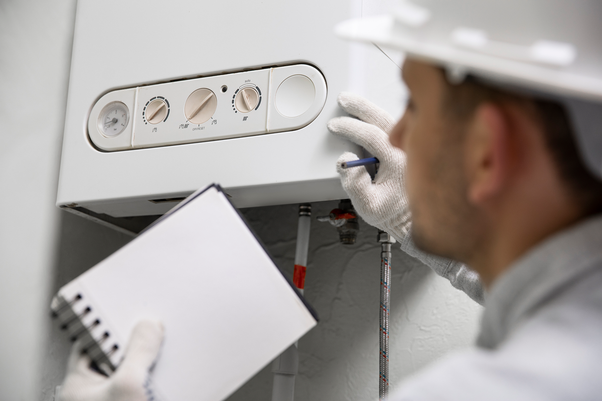 Technician in gloves checking boiler control panel with notebook