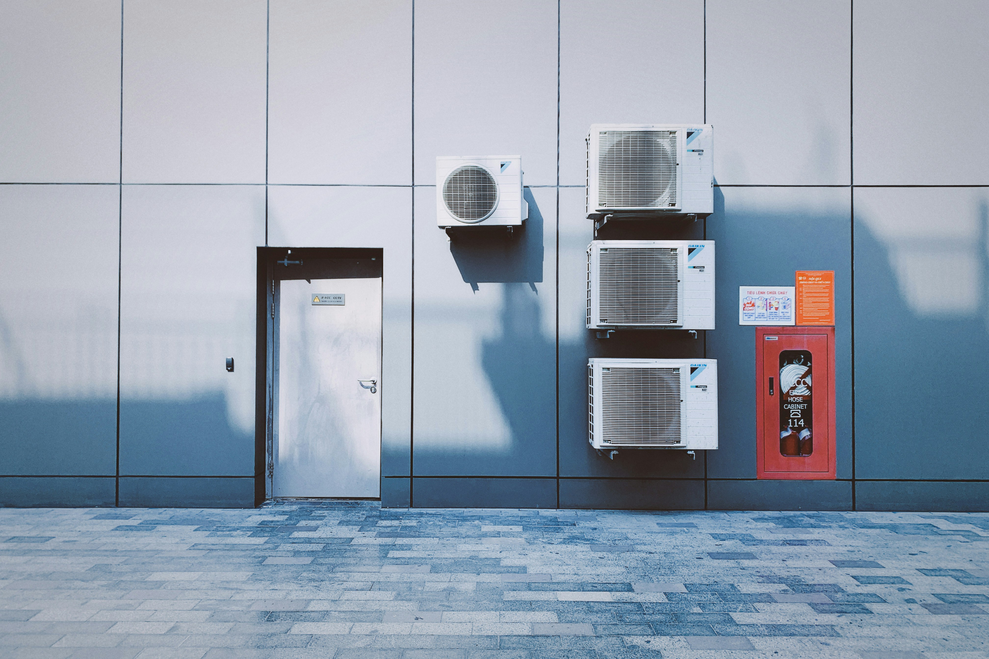 Air conditioning units and door on modern blue-gray building exterior