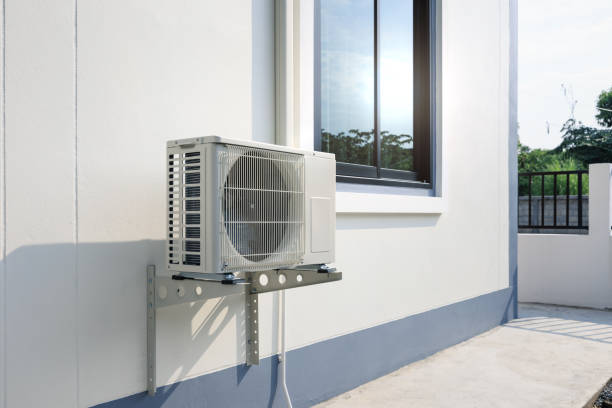 White air conditioning unit mounted on exterior wall near window