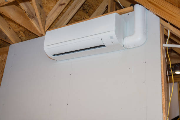 White mini-split air conditioner mounted on wall with exposed wooden roof trusses