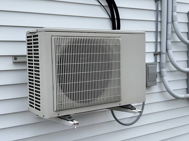 White air conditioning unit mounted on exterior wall with metal grating