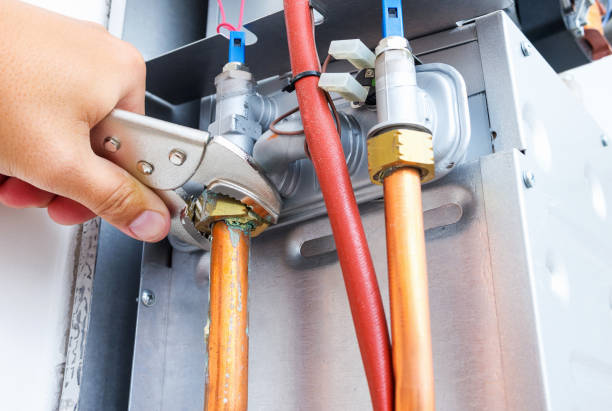 Plumber's hand adjusting copper pipes and valves in heating system