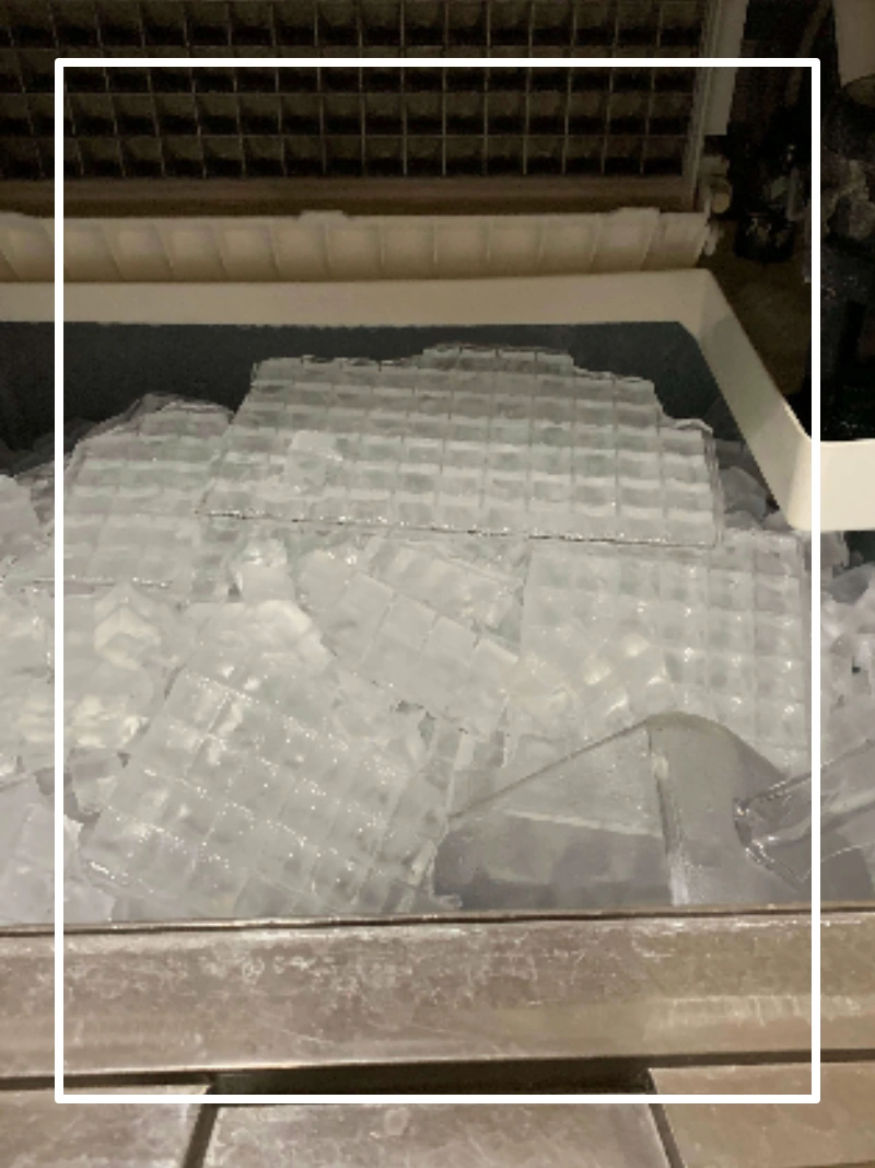 Large pile of clear ice cubes on dark surface