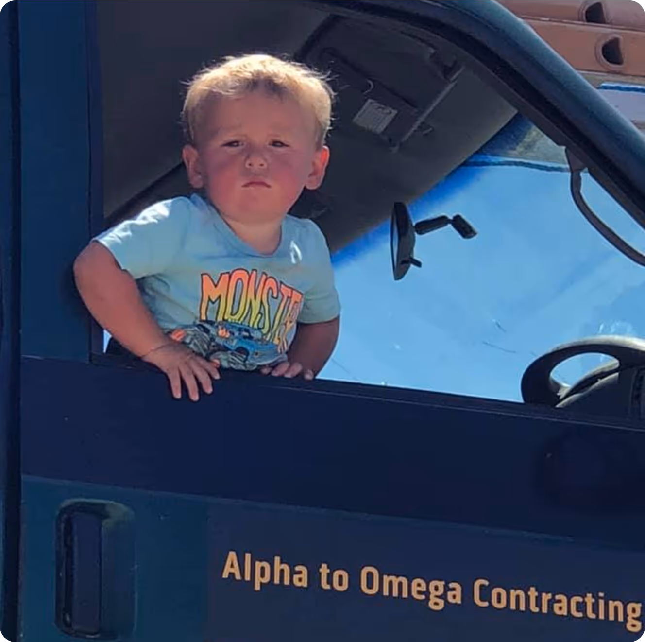 A young boy sitting in the drivers seat of a truck.