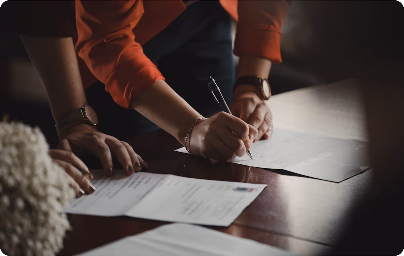 Two people sitting at a table signing papers.