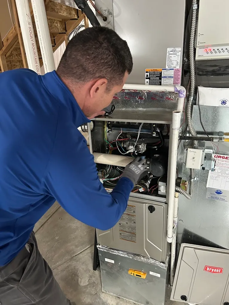 Technician inspecting and repairing a home heating furnace