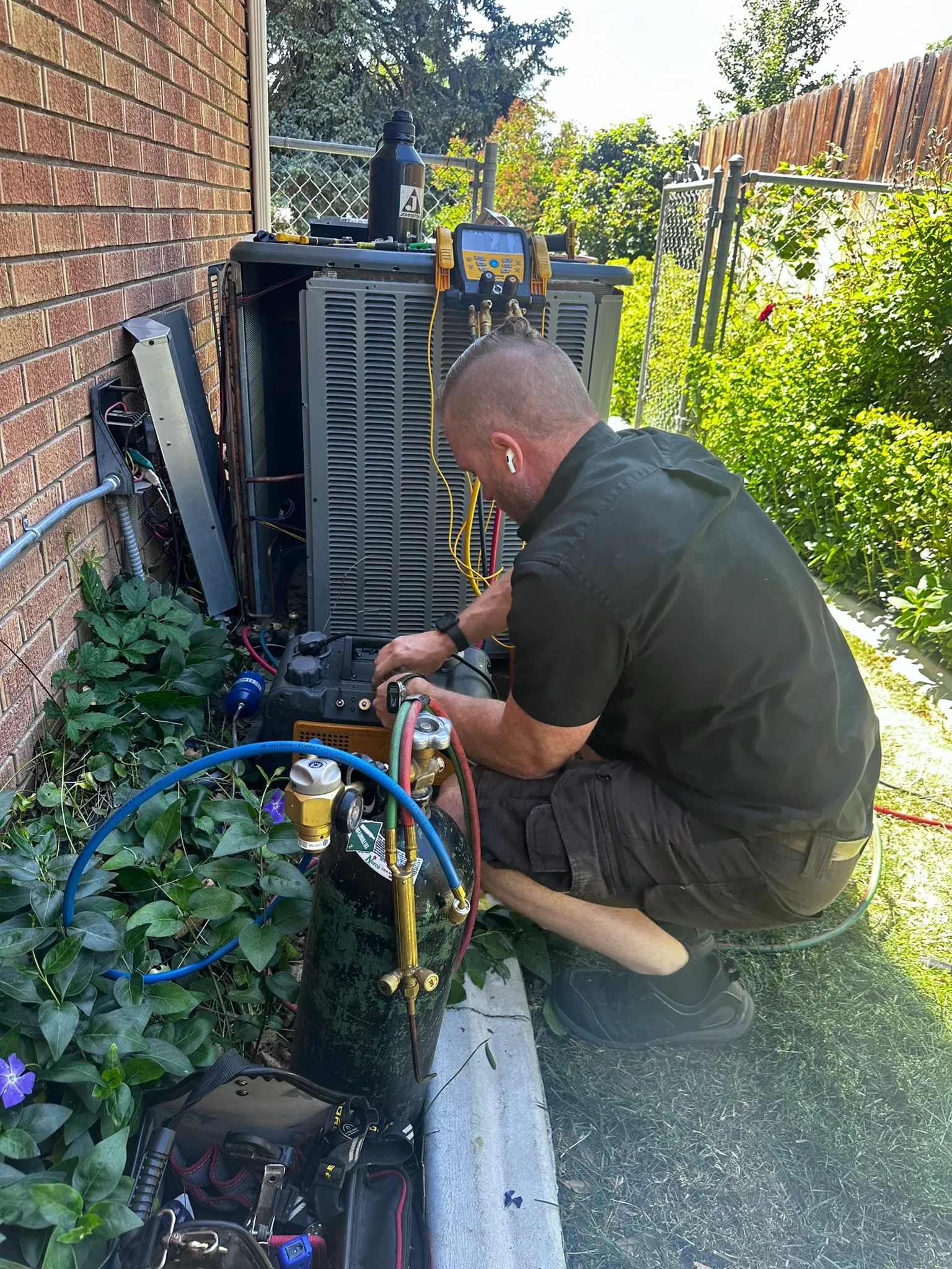 Technician performing air conditioning maintenance on an outdoor AC unit