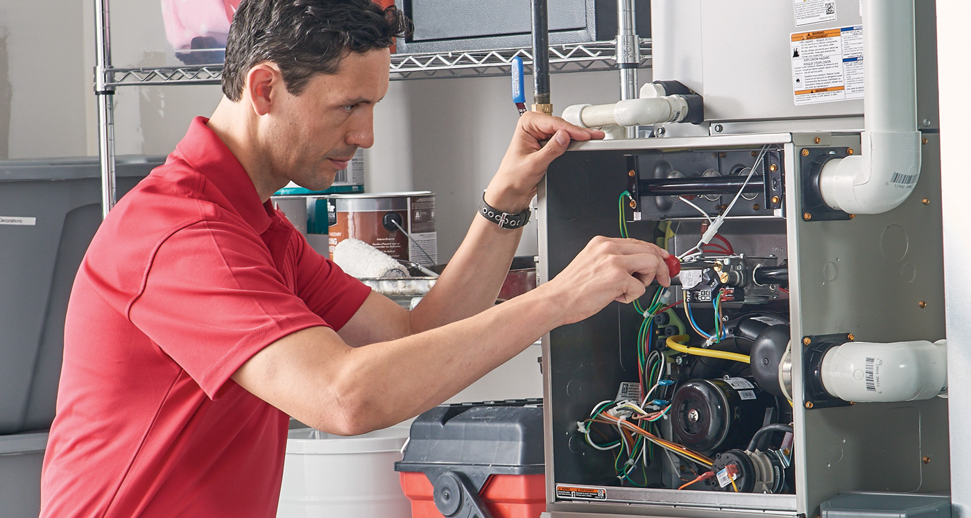 HVAC technician performing furnace repair and maintenance work on heating system components