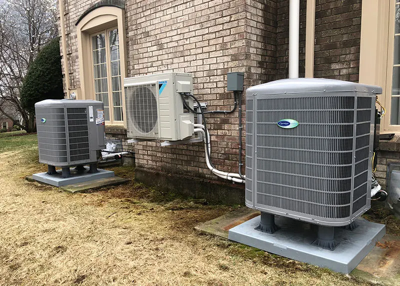 A heat pump installation in between to outdoor AC units on the exterior of a home