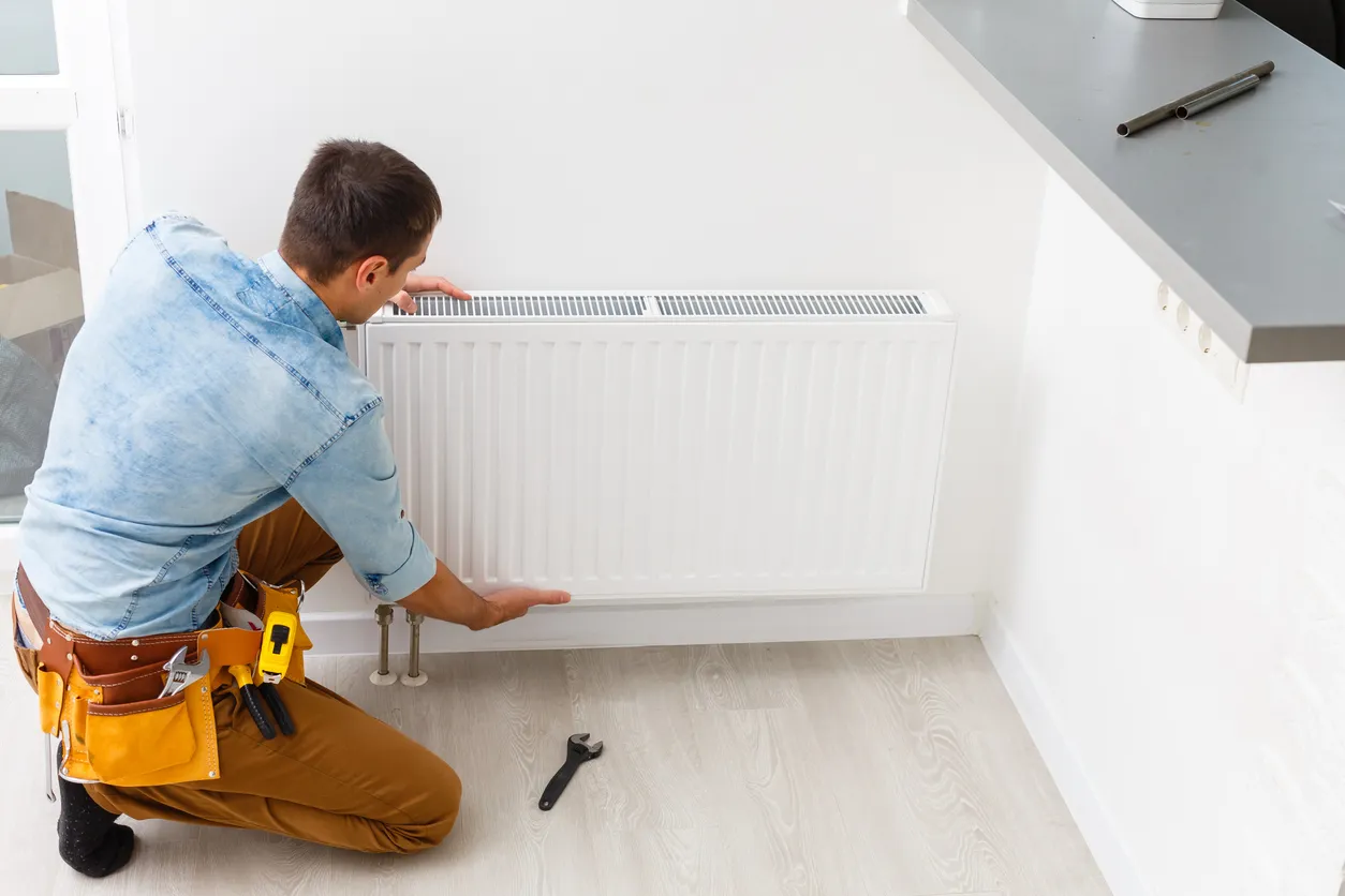 A technician in pale blue shirt installing furnace