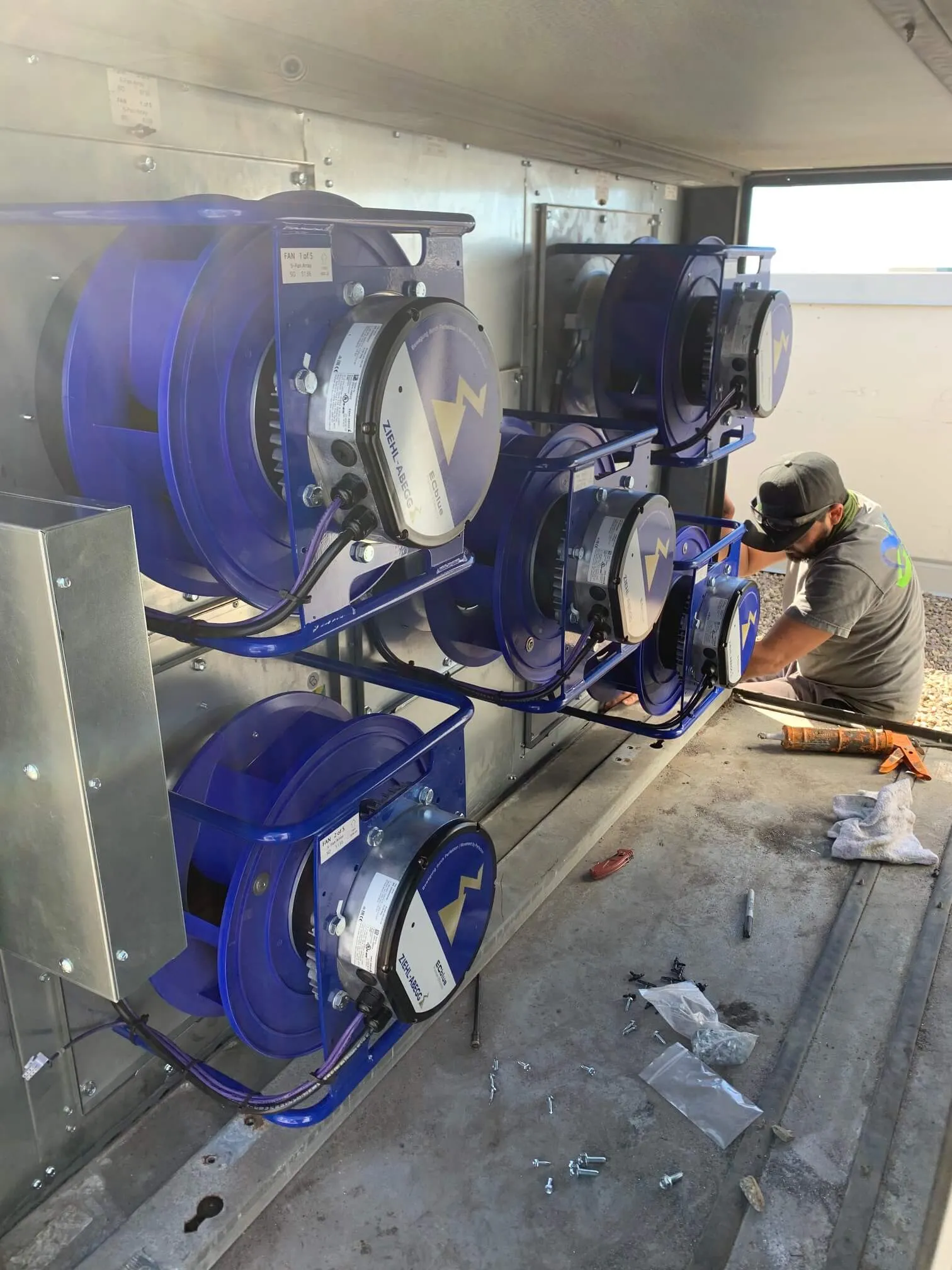 Blue industrial cable reels with technician working on electrical equipment