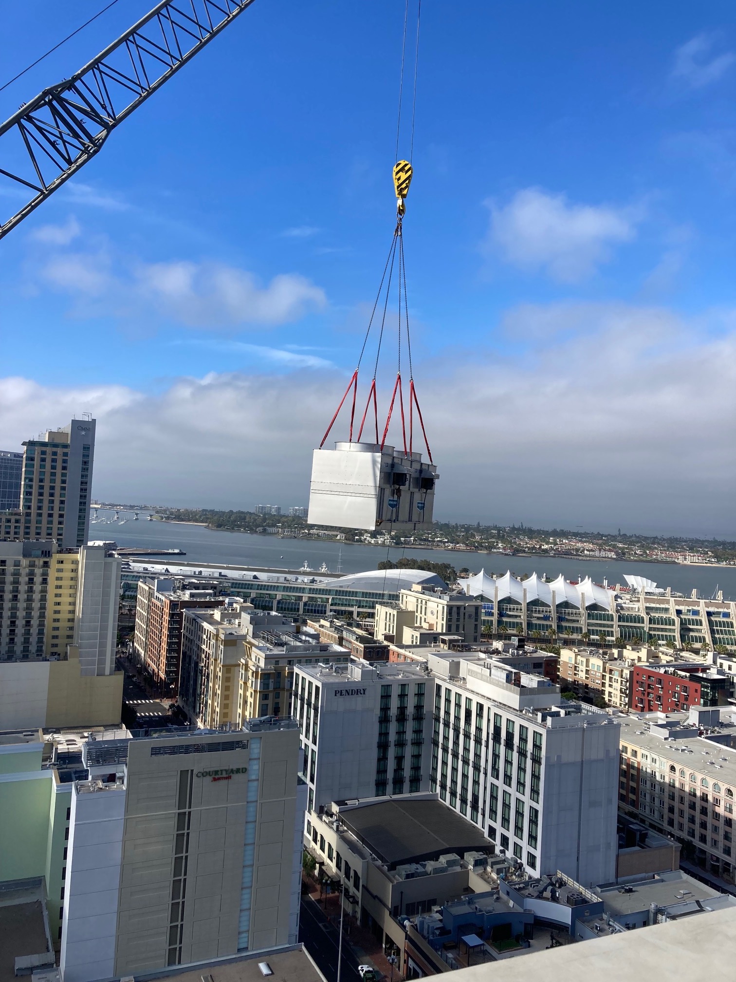 Large crane lifting heavy white block over downtown San Diego waterfront