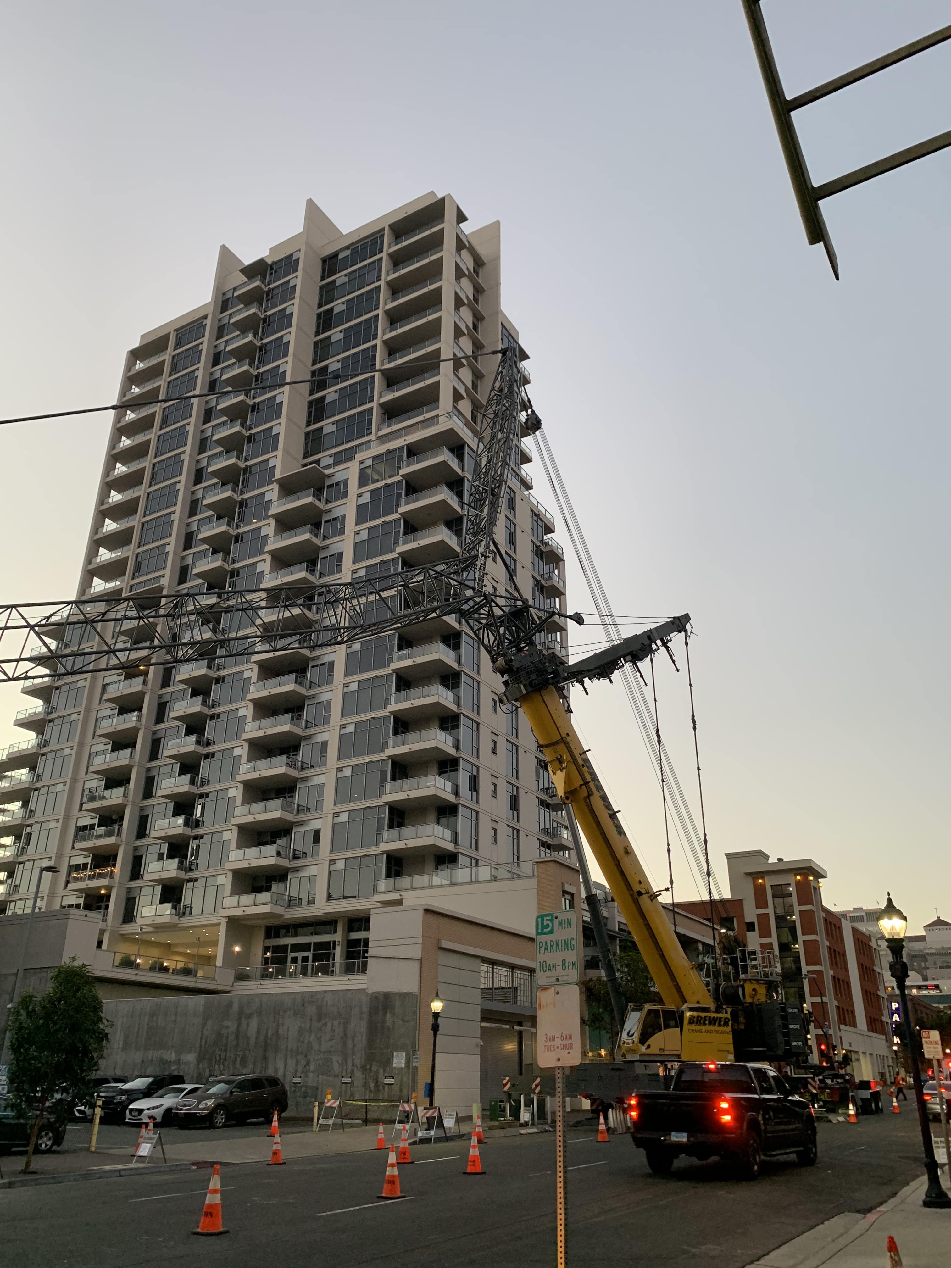Tall apartment building with crane and traffic cones at twilight