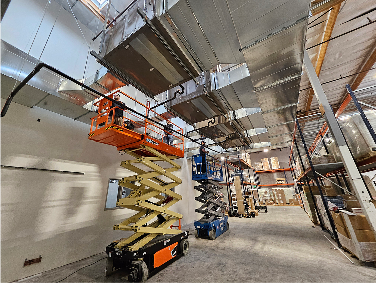 Scissor lifts and machinery inside a large industrial warehouse interior