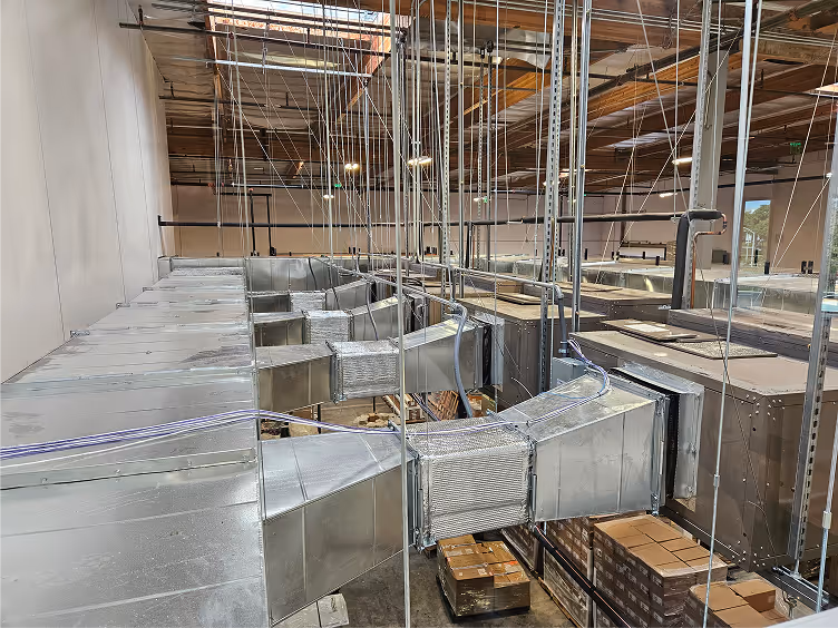 Industrial warehouse with complex metallic ductwork and stacked cardboard boxes