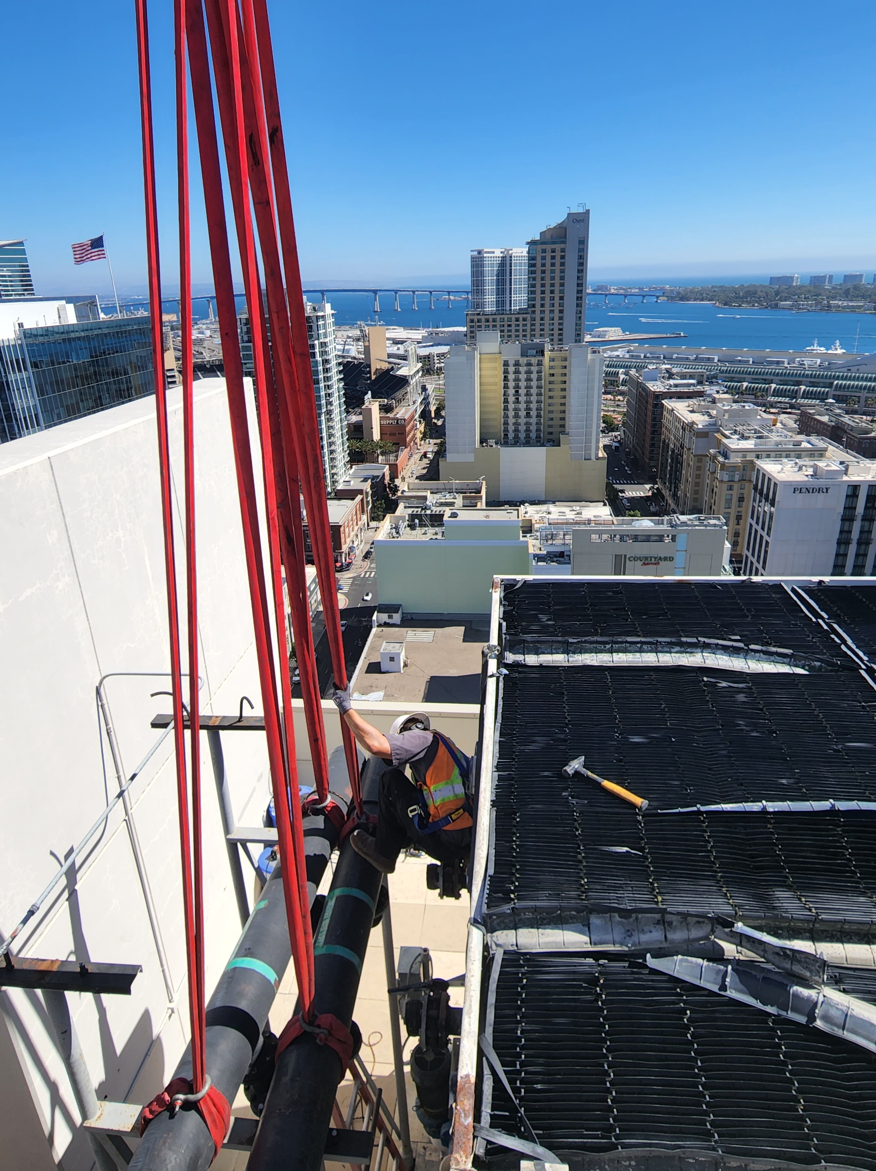 Worker on high-rise building with San Diego bay and cityscape in background