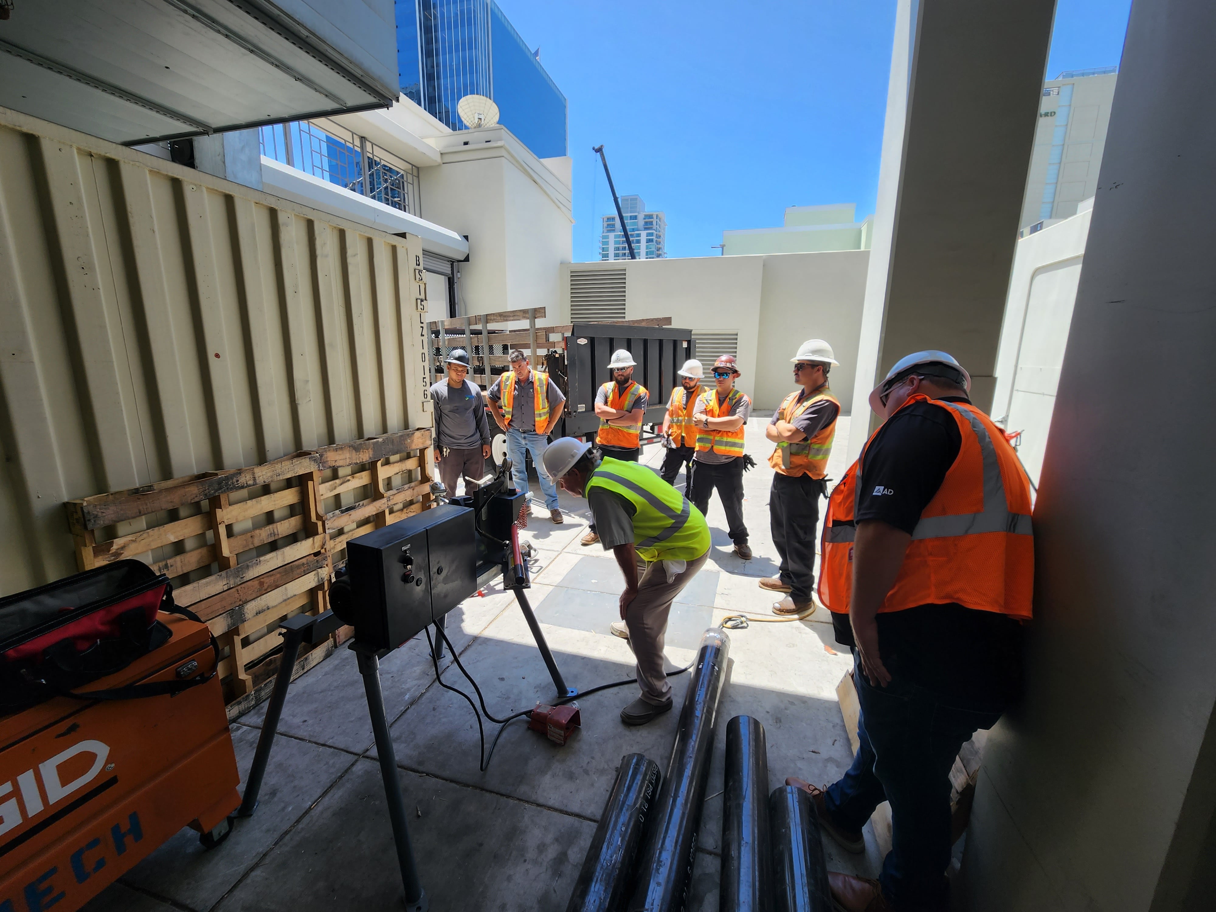 Construction workers in safety vests and helmets gather at urban worksite