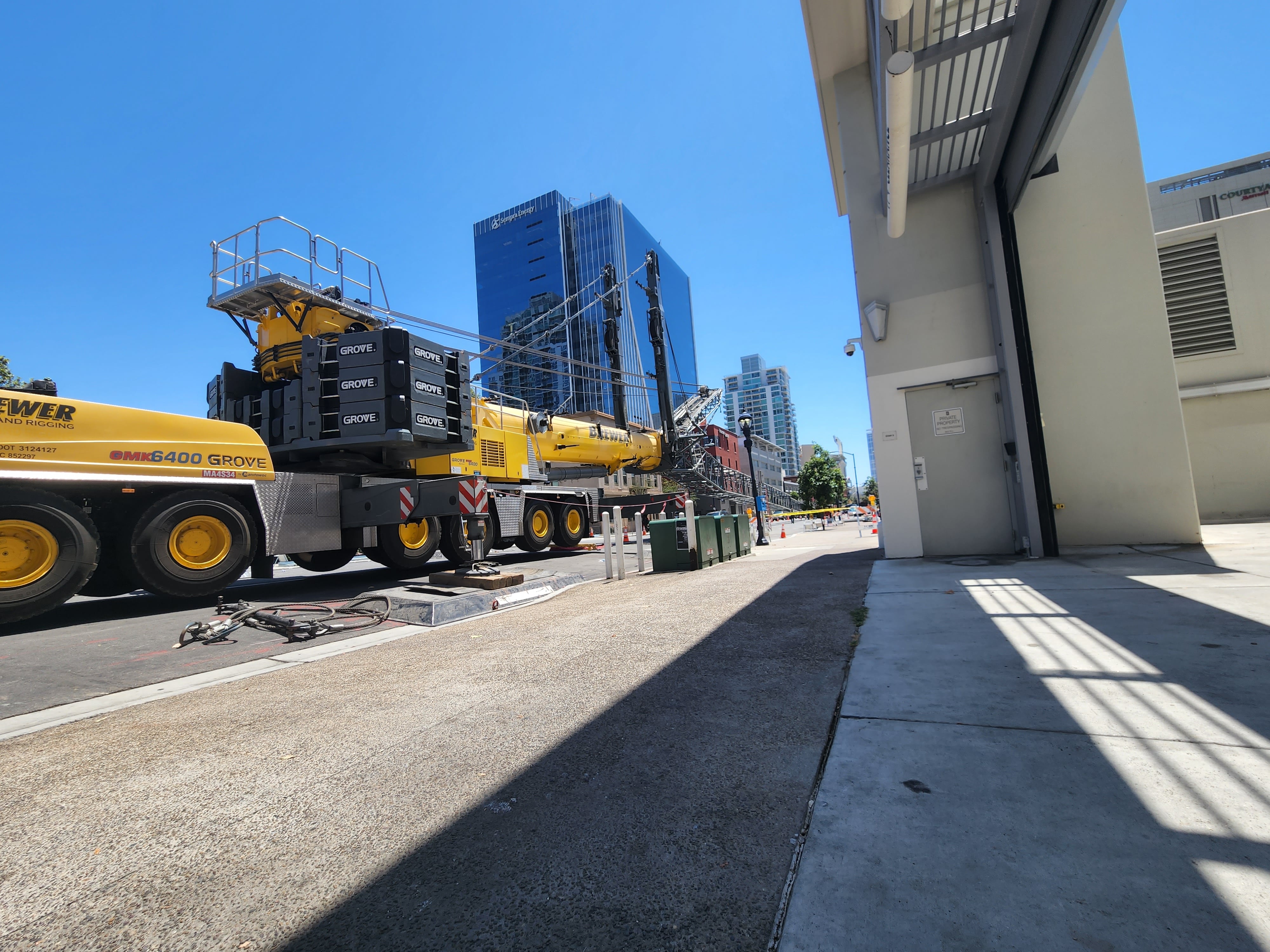Large yellow Grove crane parked on urban street with skyscrapers behind
