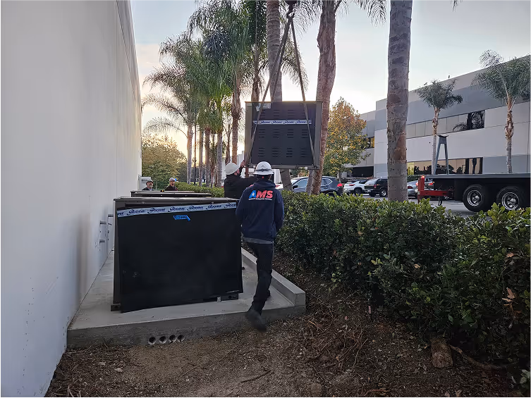 Worker in jacket installing or maintaining large black equipment outdoors